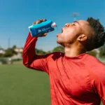 Deportista bebiendo agua tras entrenar para una buena recuperación