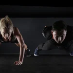 Mujer y hombre haciendo flexiones en el gimnasio