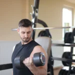 Hombre entrenando con mancuernas en el gimnasio para ganar musculo limpio