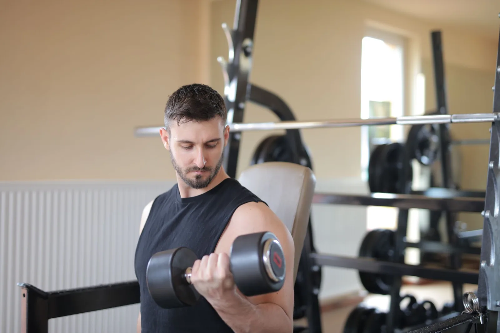 Hombre entrenando con mancuernas en el gimnasio para ganar musculo limpio