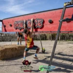 Participantes superando la lona negra con el logo de Skull Race en una carrera de obstáculos